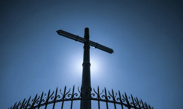 Edelstahl-Kreuz und Zaun auf blauem Himmel und Sonnenlicht Hintergrund. Kruzifix von Jesus Christus. Gott Licht und Vergebung Konzept. Kreuze, christliche Symbole. Glaube an Gott. Symbol des Glaubens. Ostern. — Stockfoto