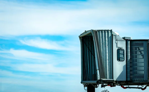 Jet bridge dopo linea aerea commerciale decollare in aeroporto contro cielo blu e nuvole bianche. Ponte di imbarco passeggeri degli aerei attraccato. Volo di partenza della compagnia aerea internazionale. Ponte a getto vuoto . — Foto Stock