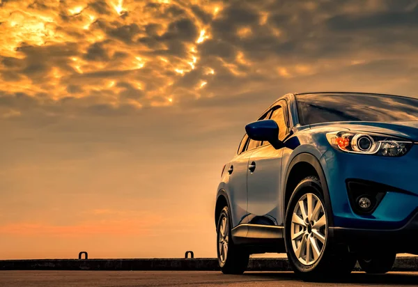Kék kompakt SUV autó sport-és modern design parkolt beton úton a tenger gyönyörű naplemente ég. Hibrid-és elektromos autó technológia koncepció. Parkolóhelyet. Autóipar. — Stock Fotó