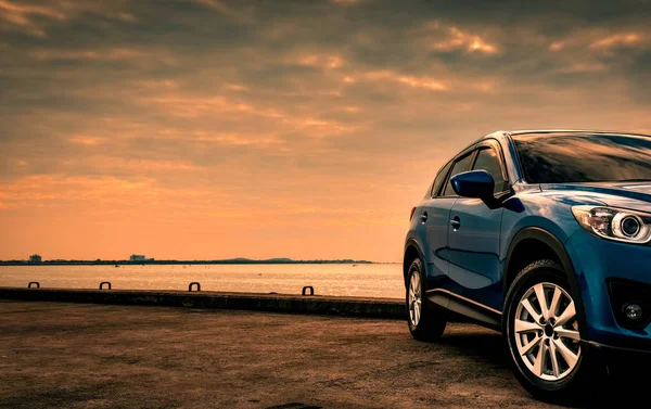 Kék kompakt Suv autó sport és a modern design parkolt a betonút a tenger a naplementét este. Hibrid és elektromos autó technológiák fogalma. Parkolóhely. Autóipar. — Stock Fotó