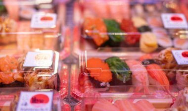 Süpermarkette rafta plastik kutu ekranda suşi seti seçici odak. Götürmek için Japon yemeği. Suşi teslimat işi. Tek kullanımlık plastik kapta yemeye hazır sağlıklı gıdalar. Öğle yemeği kutusu.