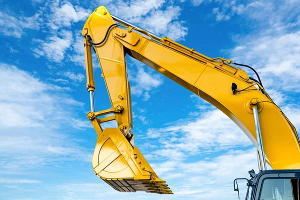 Yellow backhoe with hydraulic piston arm against blue sky. Heavy machine for excavation in construction site. Hydraulic machinery. Huge bulldozer. Heavy machine industry. Mechanical engineering. — Stock Photo, Image