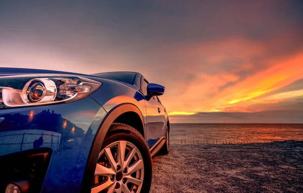 蓝色紧凑型Suv车与运动和现代设计停在日落的海滩。混合动力和电动汽车技术。停车位。汽车行业。汽车护理业务背景。美丽的天空. — 图库照片