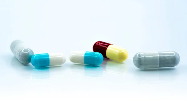 Cápsulas coloridas sobre fondo blanco. Industria farmacéutica. Interacción de la medicina herbal con otra droga. Farmacéutica. Concepto de farmacia. Pastillas de cápsulas azules, blancas, rojas y amarillas . — Foto de Stock