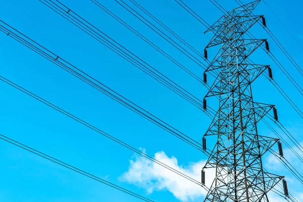 High voltage electric tower and transmission lines. Electricity pylons with blue sky and white clouds. Power and energy conservation. High voltage grid tower with wire cable at distribution station.