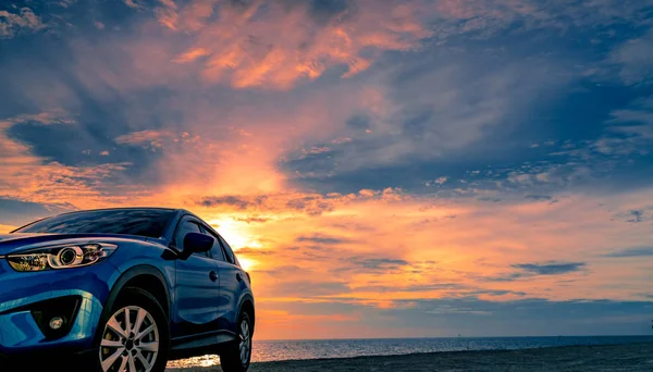 Voiture SUV compacte bleue au design sportif et moderne garée près de la plage au coucher du soleil. Technologie de voiture hybride et électrique. Place de parking. Industrie automobile. Entreprise de soins de voiture fond. Beau ciel . — Photo