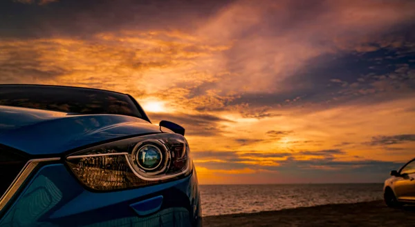 Πολυτελές μπλε αυτοκίνητο Suv σταθμευμένο στο δρόμο δίπλα στην τροπική παραλία με όμορφο ηλιοβασίλεμα ουρανό. Καινούργιο αυτοκίνητο με σπορ και μοντέρνο σχεδιασμό. Βόλτα με αυτοκίνητο για το καλοκαίρι. Αυτοκινητοβιομηχανία. Φυσικό τοπίο. — Φωτογραφία Αρχείου