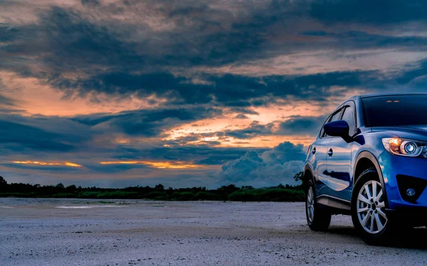 Luxus kék Suv autó parkolt szárazföldön mellett trópusi erdő gyönyörű napkelte ég. Új autó sport és modern design. Autókirándulás kalandtúrára. Természet táj. Gépjárműipar. — Stock Fotó