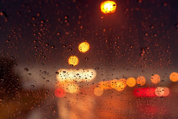 Orange night light bokeh from street light on traffic jam day. Rainy day. Transparent glass window with rain drop. Romantic weather. City life. Blur abstract background of urban light on rainy season — Stock Photo, Image