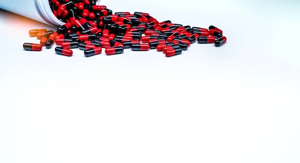 红黑抗生素胶囊药丸在白色背景下从塑料药瓶中扩散出来 抗生素耐药性 制药工业 胶囊药丸生产 — 图库照片