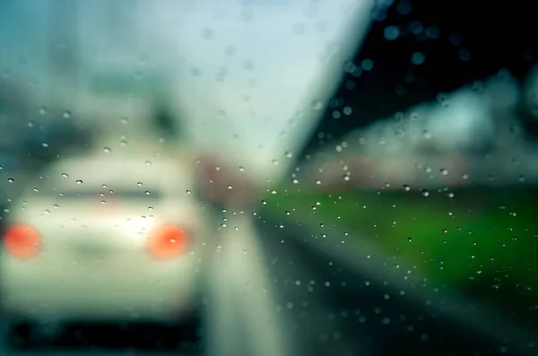 Rain drops on windshield. Car driving on asphalt road on rainy day. Windshield window of car with raindrops on glass windscreen. Traffic jam on rainy season. Bad weather in stormy day. Travel by car.