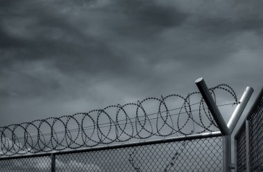 Hapishane güvenlik çiti. Dikenli tel örgü güvenlik çiti. Dikenli tel örgüler. Bariyer sınırı. Sınır güvenlik duvarı. Suçluları ya da teröristleri tutuklamak için. Özel alan. Askeri bölge kavramı. 