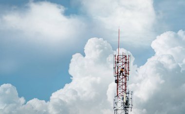 Mavi gökyüzü ve beyaz bulutlu telekomünikasyon kulesi. İşçi telekomünikasyon kulesine 5G ekipman yerleştirdi. İletişim teknolojisi. Telekomünikasyon endüstrisi. Mobil veya telekom 5g ağı.