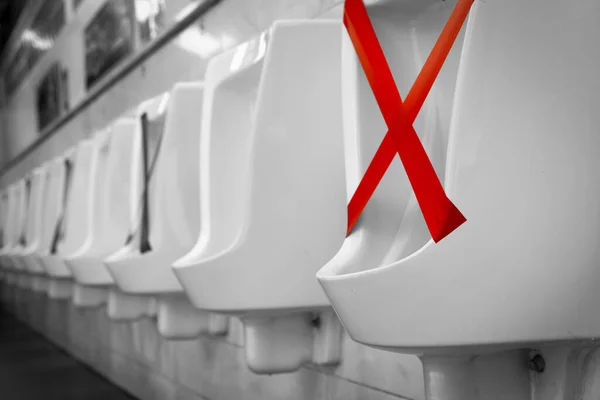 White ceramic urinals in men public toilet. Social distancing in men restroom to prevent coronavirus pandemic. Man bladder health with urinary incontinence problem. Urine infections. Male latrine WC.