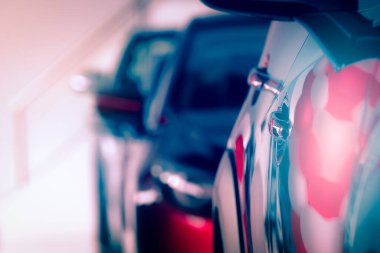 Bulanık kırmızı araba modern sergi salonuna park edilmiş. Araba galerisi ve oto kiralama konsepti. Otomotiv endüstrisi. Modern lüks sergi salonu. Arka arkaya park edilmiş yeni parlak bir araba. Elektrikli otomobil teknolojisi. 