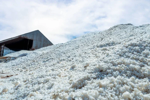 Brine salt farm warehouse with sky and clouds. Pile of organic sea salt. Raw material of salt industrial. Ocean salt. Sodium chloride mineral. Evaporation and crystallization of sea water. Iodine.