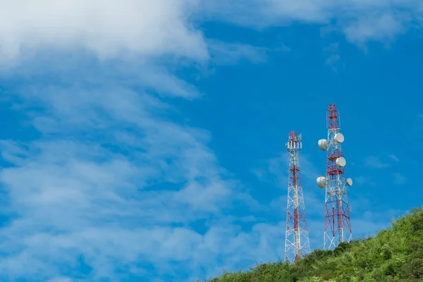 Telecommunication tower on mountain and green tree with blue sky. Antenna on blue sky. Radio and satellite pole. Communication technology. Telecommunication industry. Mobile or telecom 4g network.