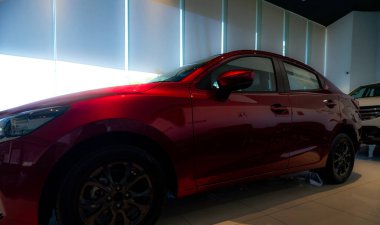 Lüks modern sergi salonuna park edilmiş kırmızı, parlak bir araba. Satılık spor tasarımı olan yeni bir araba. Araba galerisi ve oto kiralama konsepti. Elektrikli araba teknolojisi ve iş konsepti. Otomatik satış mağazası.