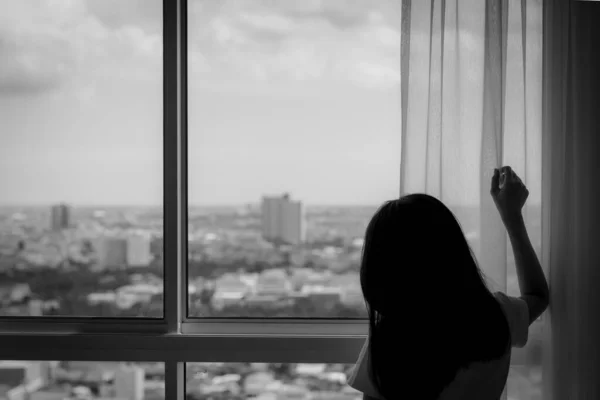 Pandangan Belakang Wanita Memegang Tirai Dan Melihat Keluar Dari Jendela — Stok Foto