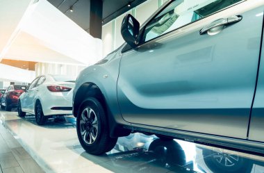 Modern galeriye park edilmiş yeni bir araba. Araba kiralama ve araba kiralama konsepti. Kırmızı, beyaz ve gümüş araba stokları galeri ofisinde satılıktır. Modern lüks sergi salonu. Elektrikli taşıt işi.