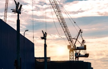 Gün batımında gökyüzüne karşı siluet inşaat vinci. İnşaat alanında vinç gereçleri kullanın. Kiralık konsept için. İnşaat işi için Crane bayiliği. Emlak endüstrisi.