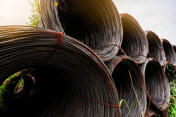 Steel wire coil with sunlight sky. Metal steel reinforced for concrete construction. Iron wire for construction industry. Spool or roll of silver steel wire. Metal materials. Rusty steel wire coil.