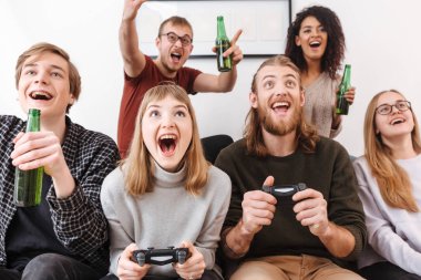 Kanepede oturan ve birlikte video oyunları oynamak ve evde bira içmeye vakit heyecan arkadaşlar fotoğraf kapatmak 