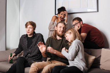 Kanepe ve frightenedly izlerken korku filmi ile birlikte bira evde oturan genç korkmuş arkadaşlar portresi