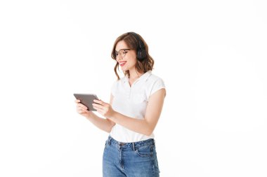 Gözlük ve ayakta ve mutlu bir şekilde tablet izole beyaz arka plan üzerinde seyir siyah kulaklık güzel gülümseyen Bayan portresi