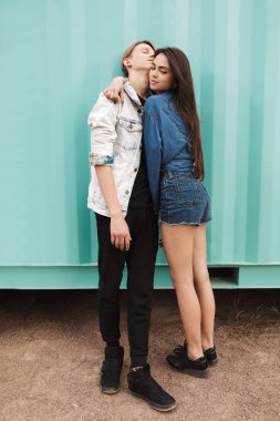 Güzel genç mavi arka plan üzerinde duran üzerinde birbirlerine kucaklayan çift