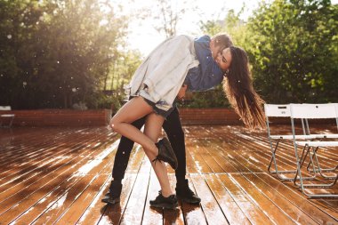 Genç neşeli çift Park'ta yağmur altında dans ederken sarılma. Güzel çift birlikte vakit