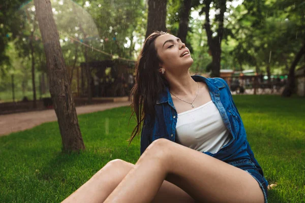 Şort Sersem Park Yağmur Altında Çimenlerin Üzerinde Otururken Gözlerini Kapatma — Stok fotoğraf