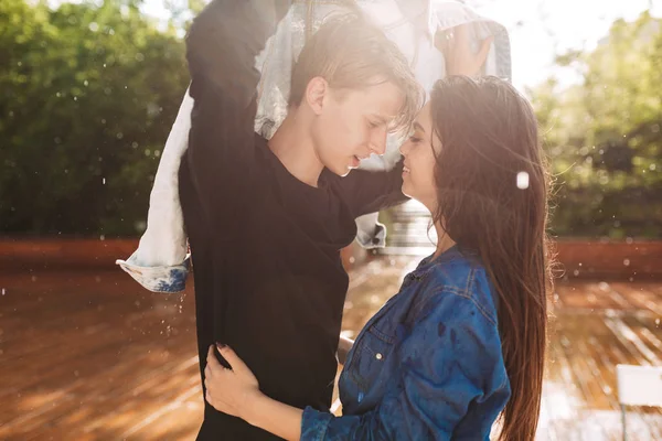 Genç çift kendilerini Park'ta yağmur altında dururken denim ceket ile kapsayan portresi. Güzel çift birlikte vakit