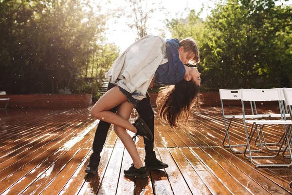 若いカップルが公園で雨の下で踊りながらハグの美しい写真 — ストック写真