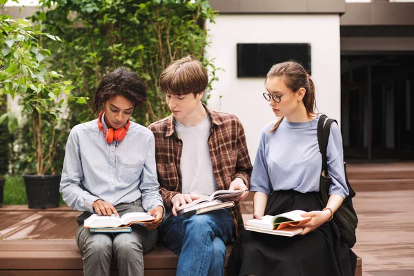 Skupina Studentů Sedí Lavičce Zamyšleně Čtení Knih Nádvoří Univerzity Společnost — Stock fotografie