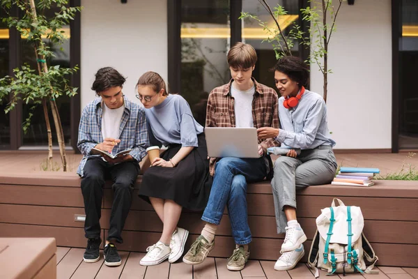 Grupo Estudantes Sentados Banco Usando Laptop Livro Leitura Enquanto Passar — Fotografia de Stock