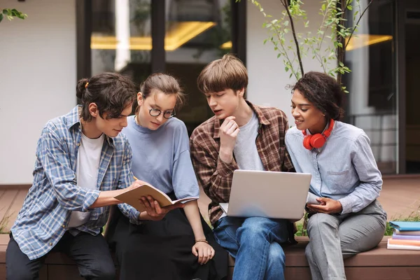 Foto Studenti Seduti Sulla Panchina Con Computer Portatile Prenotare Mentre — Foto Stock