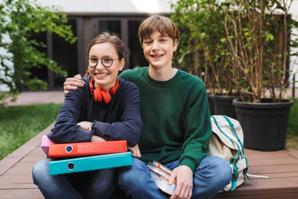 Coppia Giovani Studenti Seduti Con Cartelle Libri Mano Gioiosamente Guardando — Foto Stock