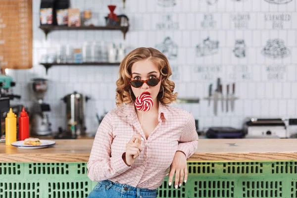 バーで座っているサングラスで美しい女性キャンディーと Amazedly カフェのカメラで探してカウンター — ストック写真