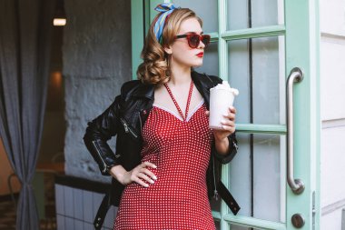 Güzel bayanın el milkshake ile kafede kapının yanında duran ve düşünceli bir kenara seyir güneş gözlüğü