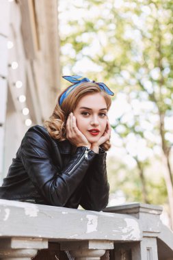 Güzel Bayan deri ceket ayakta ana sersem kamera açık bakarken ellerinde yaslanmış