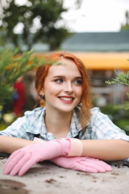 Pembe eldivenleri mutlu bir kenara serada çalışırken seyir oldukça gülümseyen çiçekçi portresi