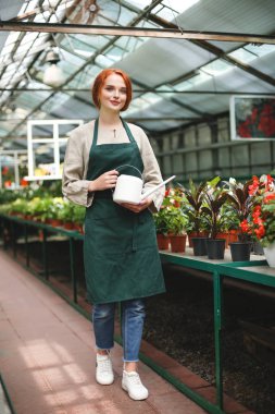 Sulama olabilir elinde ile ayakta ve sevinçle kamera seyir serada önlük güzel çiçekçi