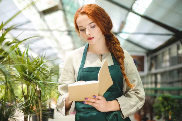 Ayakta ve düşünceli serada çalışırken Not Defteri'nde yapma önlük güzel çiçekçi