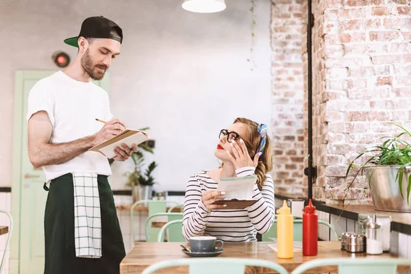 Pretty Lady Eyeglasses Sitting Table Menu Hands Thoughtfully Looking Waiter — Stock Photo, Image