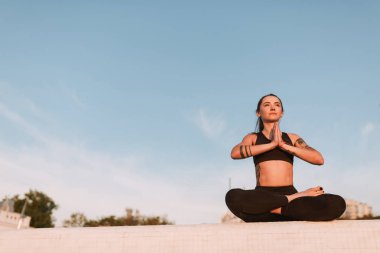 Lotus poz oturan ve sersem bir kenara bakıyor güzel bayan. Genç kadın siyah spor top ve tozluk süre pratik yoga meditasyon