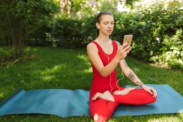 Foto Kvinna Röd Overall Som Sitter Lotus Pose Yogamattan Park — Stockfoto