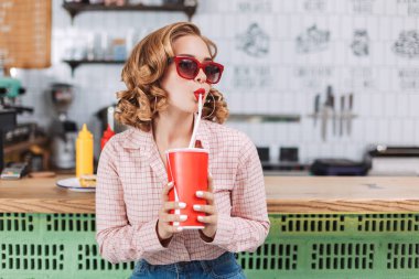 Güzel Bayan güneş gözlüğü ve barda oturan gömlek counter ve bir kenara kafede bakarken soda su içme