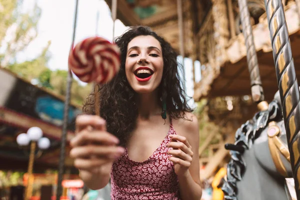 Şekerle elinde duran ve sonsuza dek mutlu kamera eğlence parkı zaman harcama süre seyir elbise siyah kıvırcık saçlı güzel Bayan