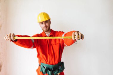 Turuncu iş elbiseleri ve izole mezura kullanarak Sarı kask Oluşturucu kapatın